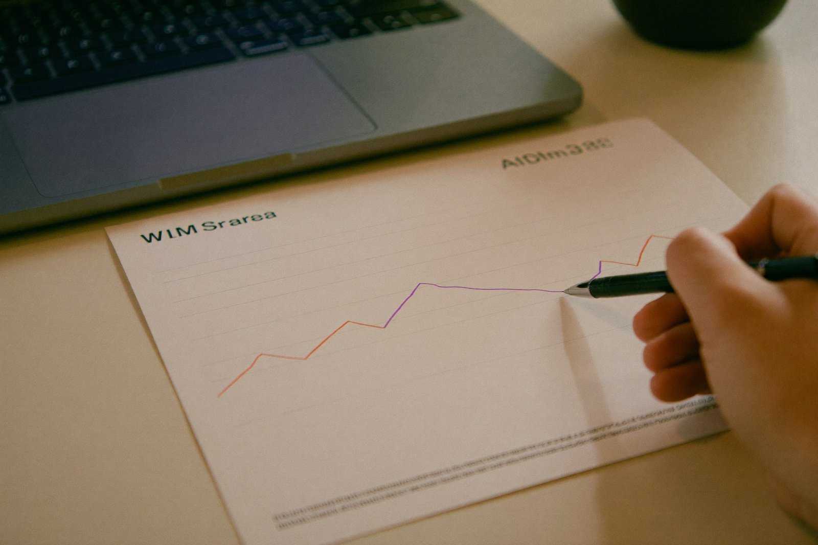 A close-up of a printed static ad mockup on a desk beside a laptop showing a performance graph