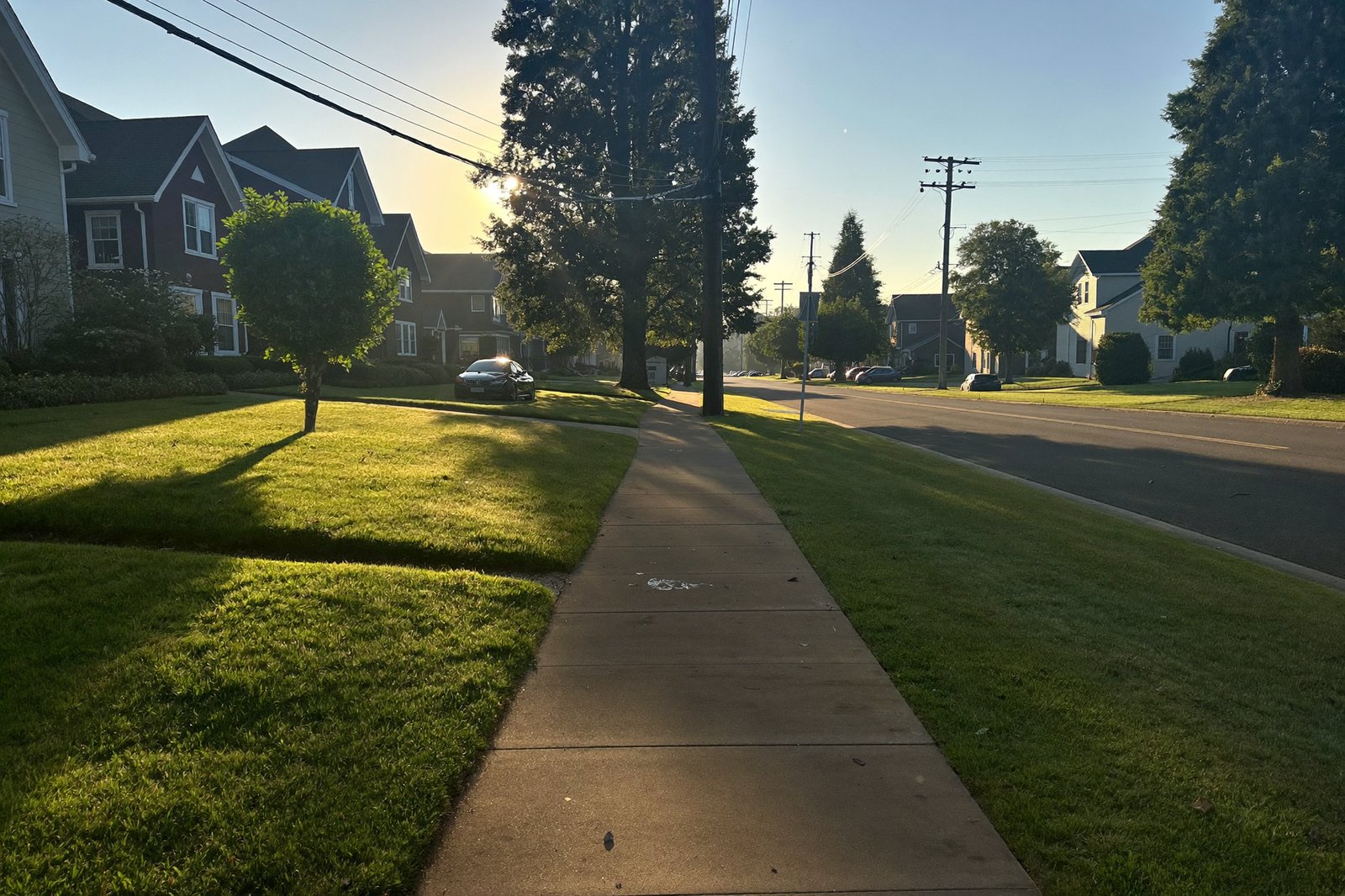 Early morning walk on a quiet neighborhood street, long shadows, empty sidewalk ahead