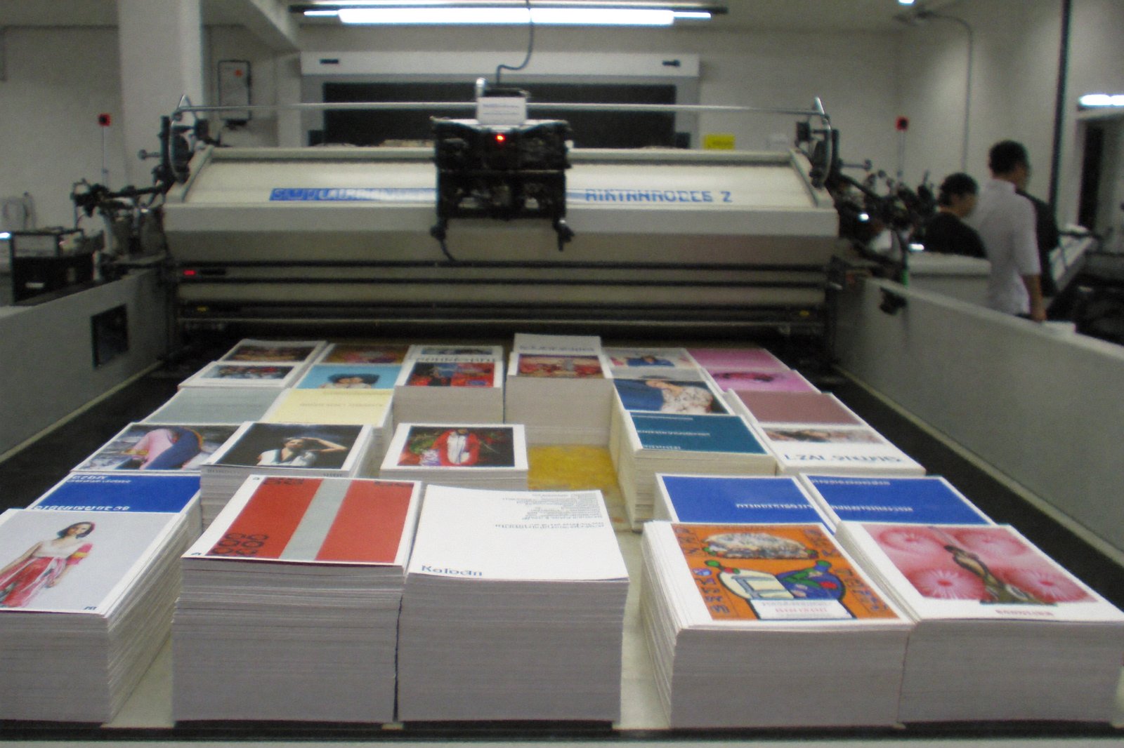 A studio printer producing stacks of printed ad variations, sorted piles on the table beside it