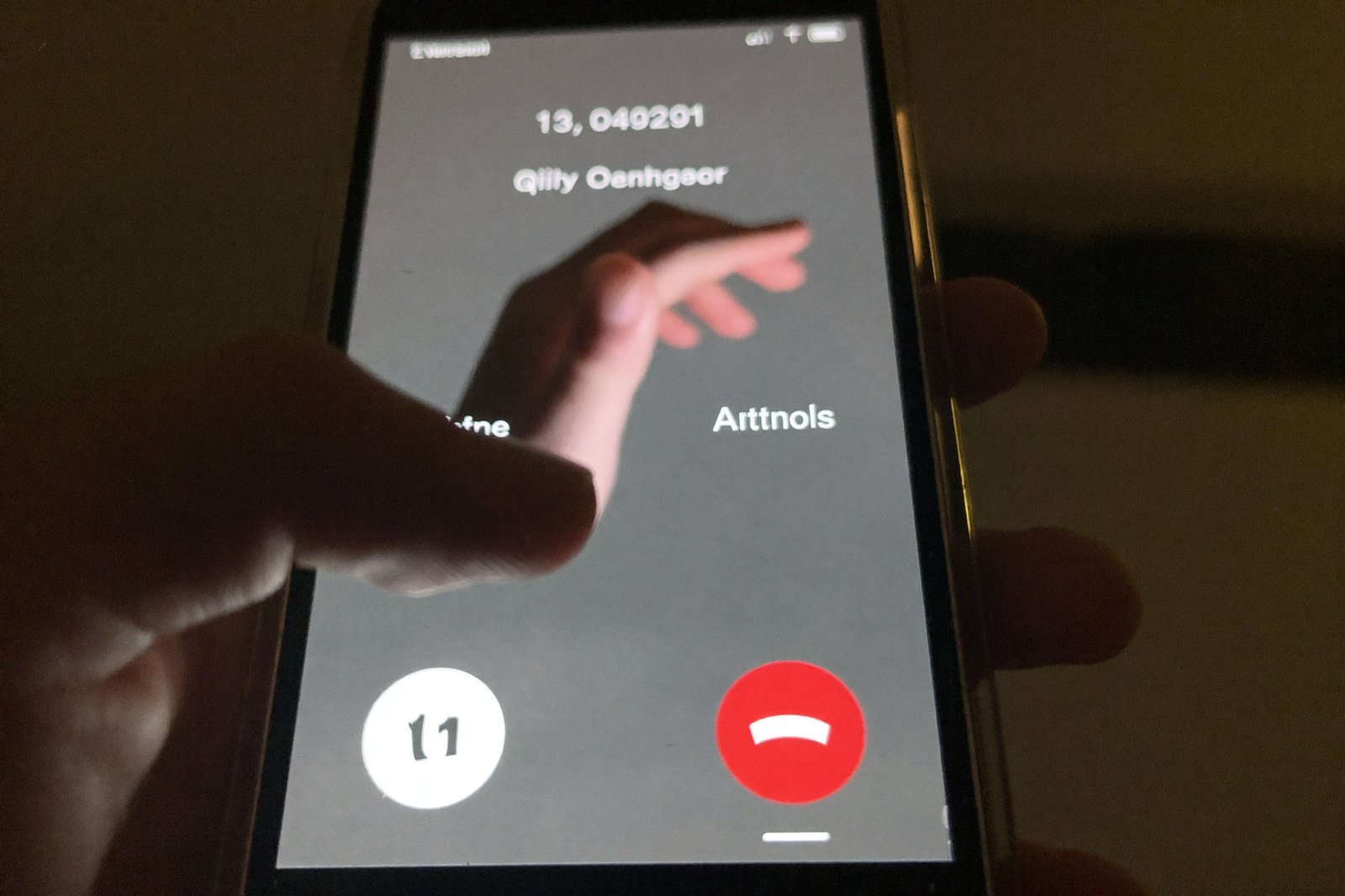 Close-up of a phone screen showing an unknown incoming call in a dim room