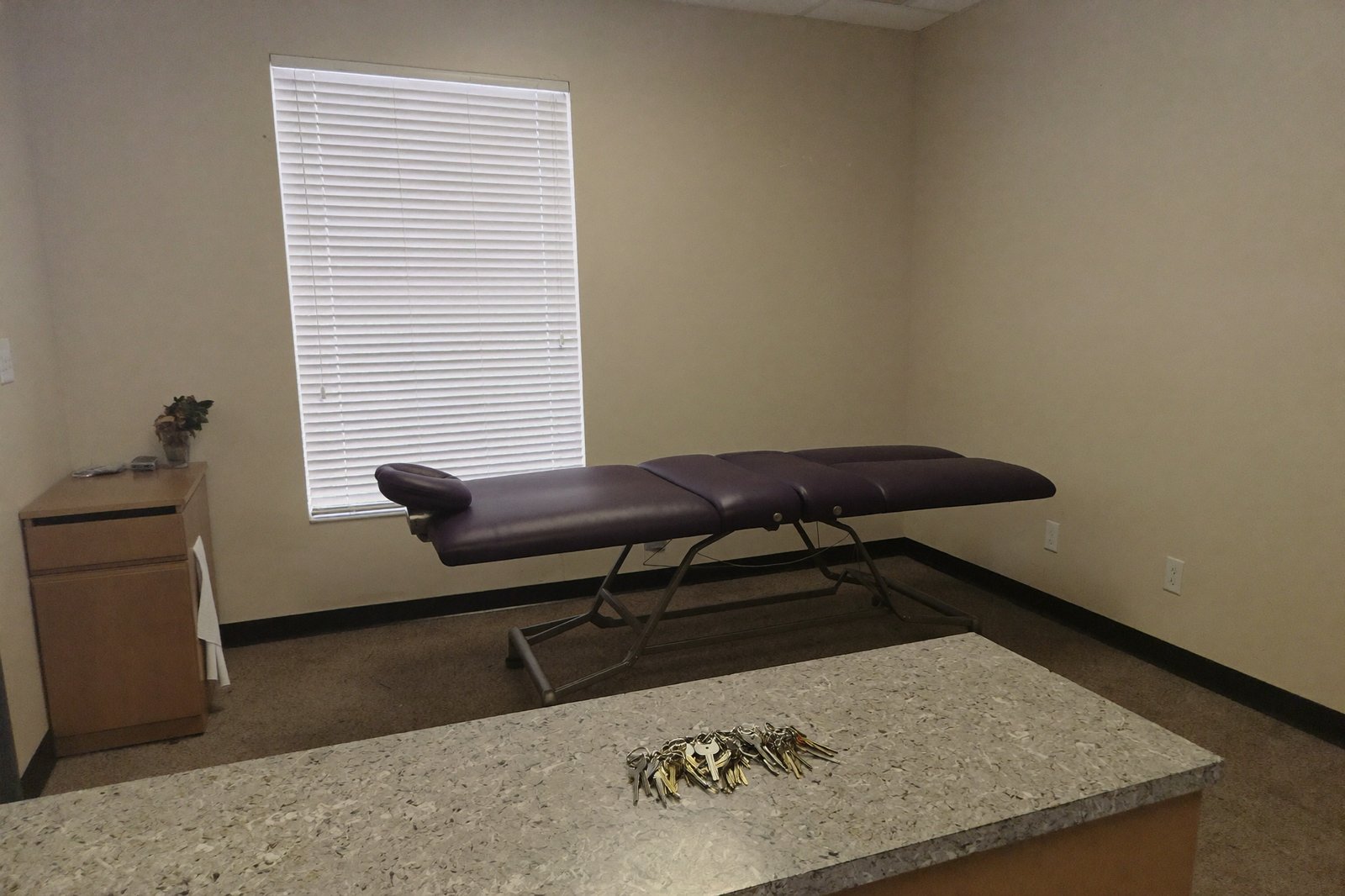 An empty, clean chiropractic treatment room with keys on the front desk